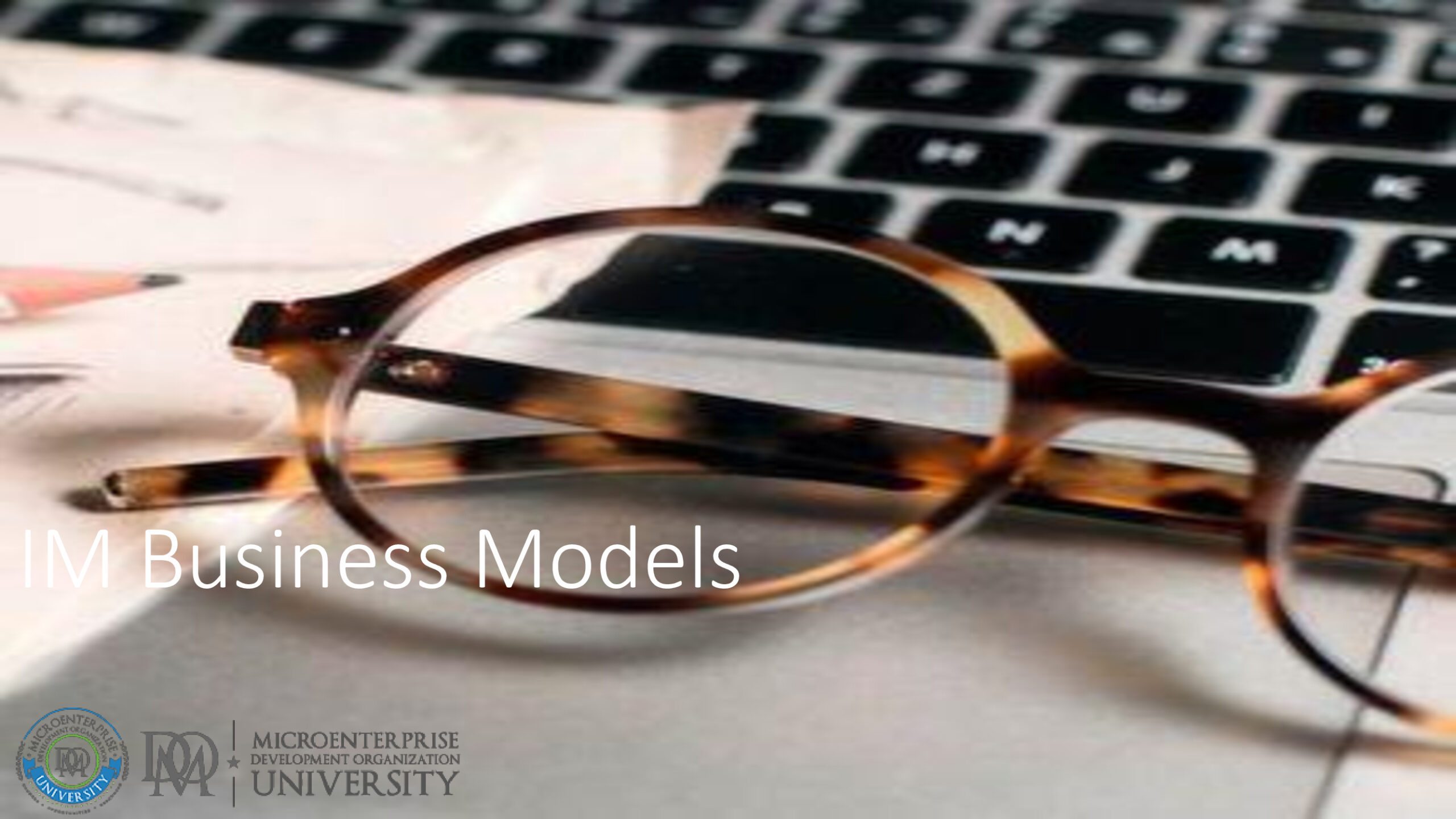 Round eyeglasses on laptop keyboard and documents