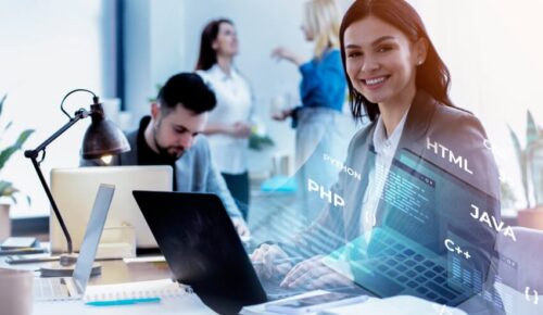 Smiling female developer coding on laptop in office