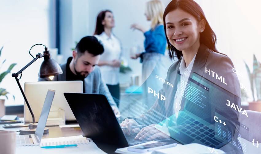 Smiling female developer coding on laptop in office