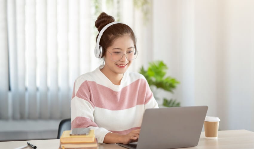 Smiling woman with headphones using laptop